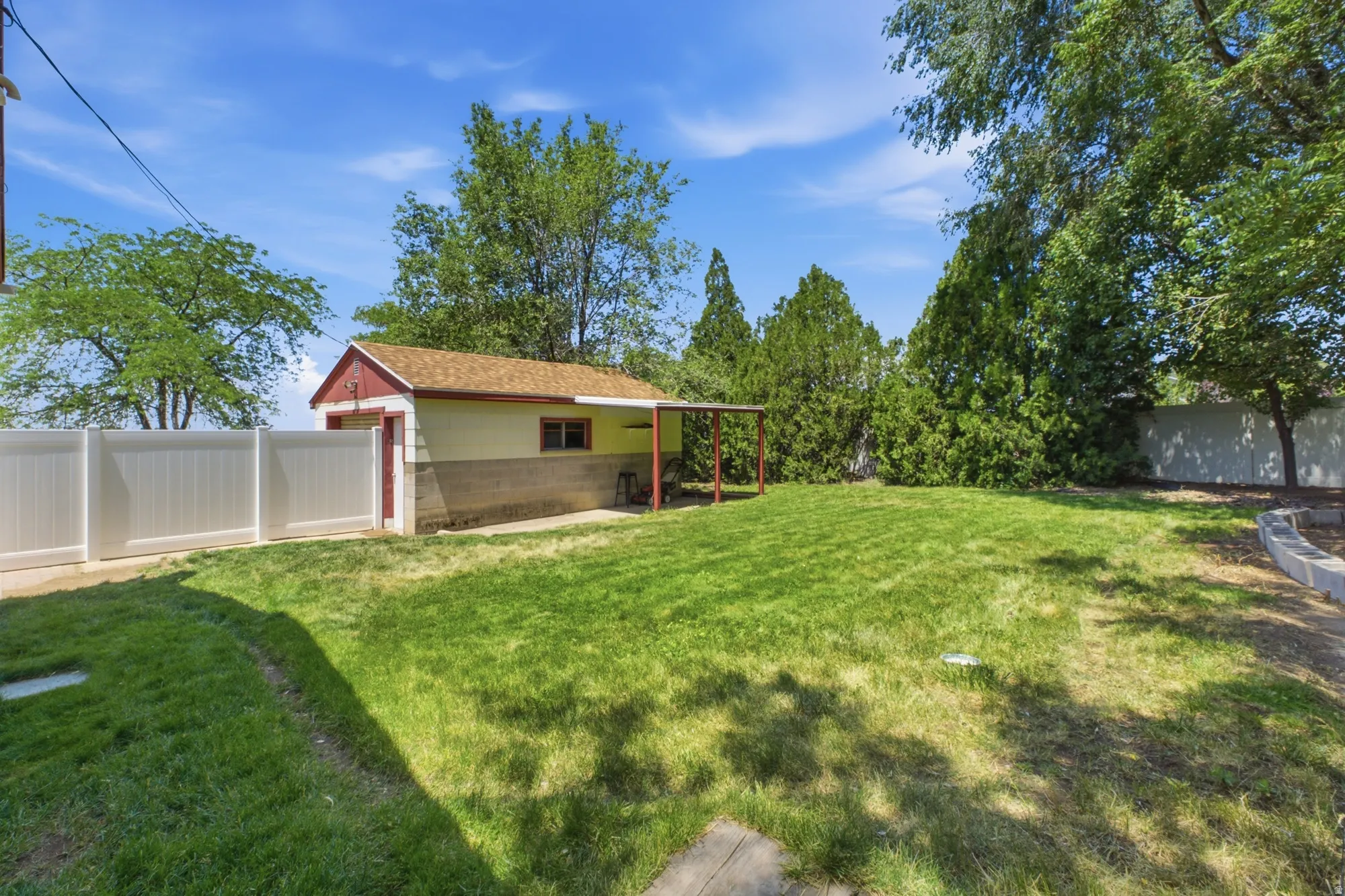 Spacious backyard with mature greenery, detached garage, and room for outdoor enjoyment.
