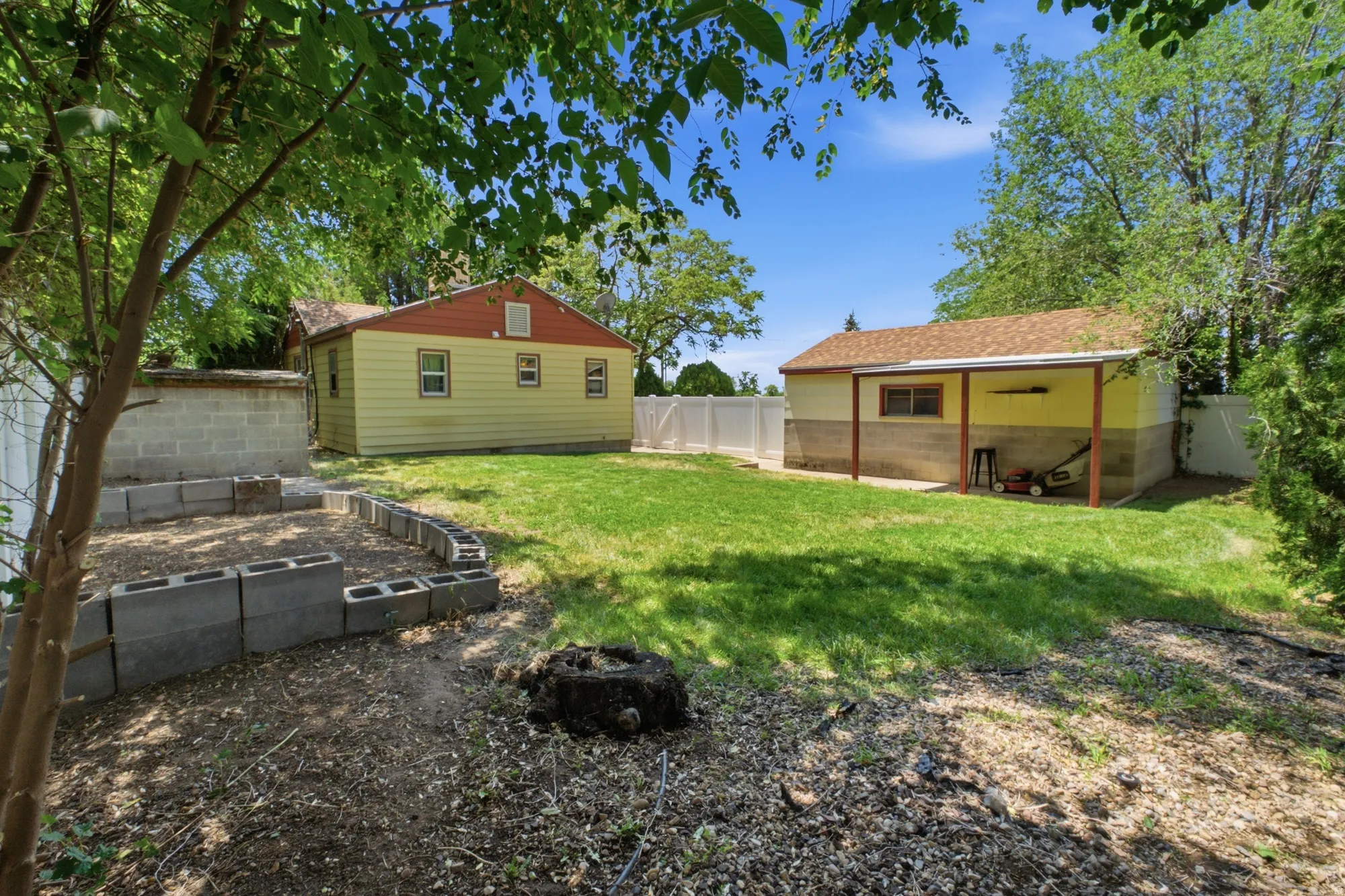 Backyard view showing the detached garage, fenced yard, and additional garden or landscaping space.