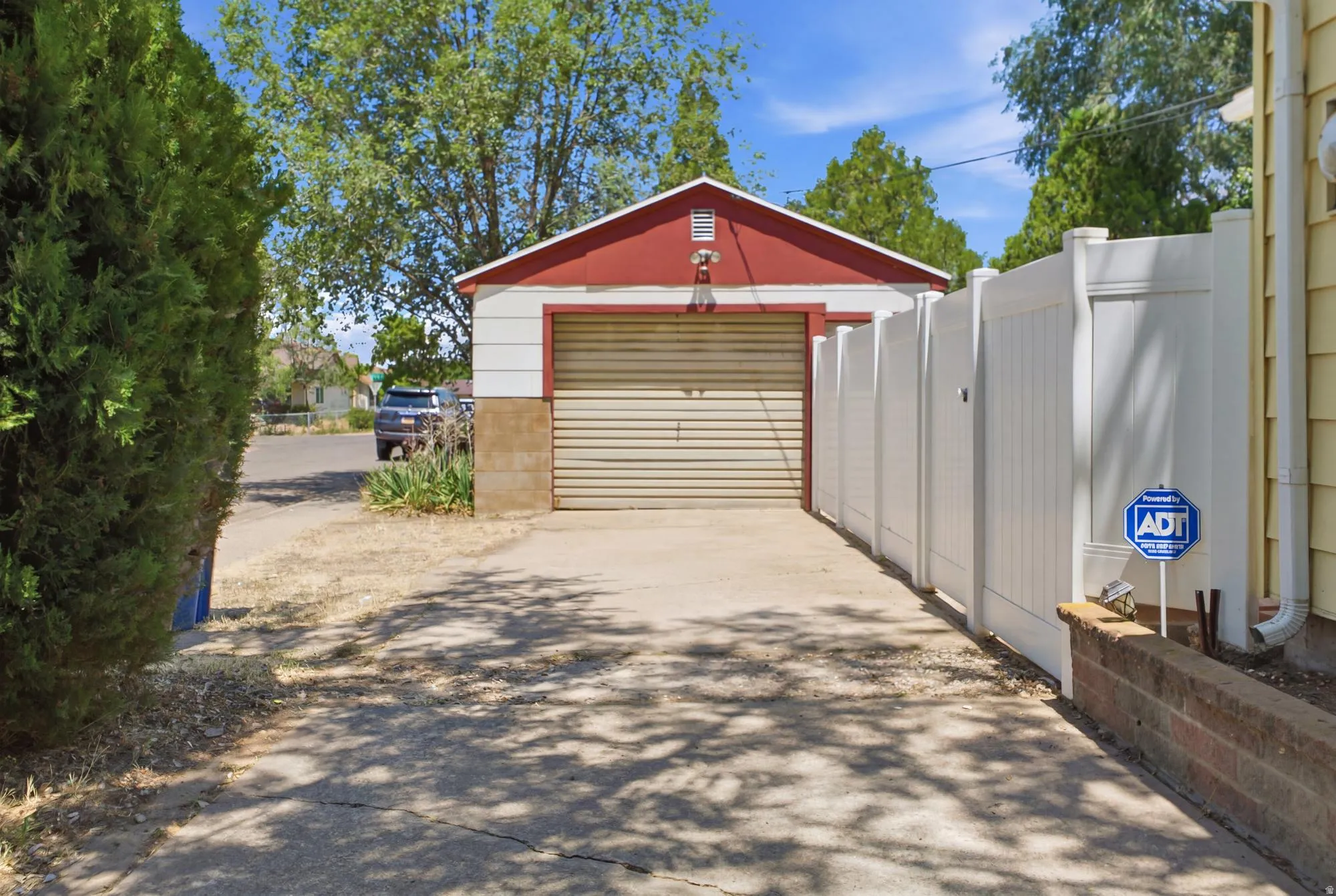 Driveway access leading to the detached garage with additional parking and gated yard entry.