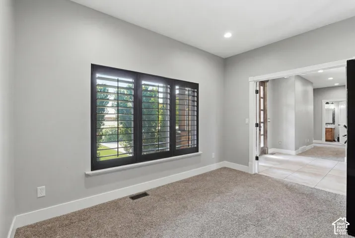 Interior room featuring a large window with dark plantation shutters, light gray walls, and plush carpeting