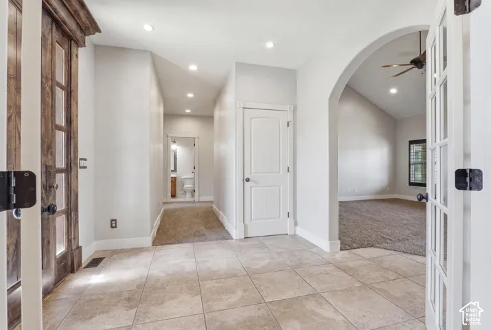 Entryway featuring large format tile flooring, a vaulted ceiling, recessed lighting, and an arched doorway leading to a carpeted room
