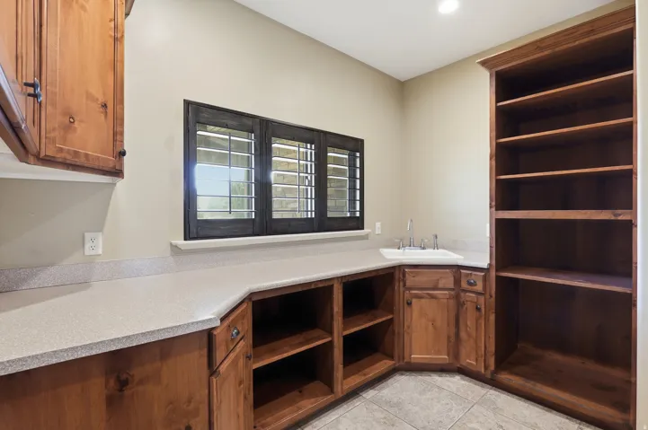 Functional utility space featuring extensive wood cabinetry, a recessed sink, and built-in shelving