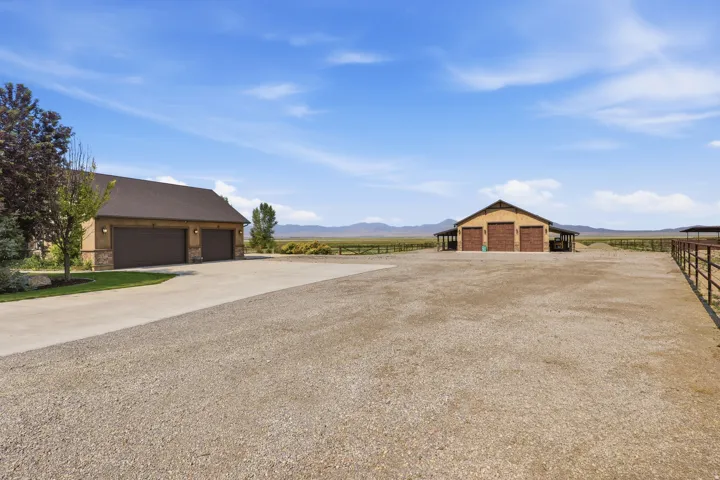 Expansive gravel grounds featuring a multi-bay barn structure, a separate two-car garage building, and perimeter fencing