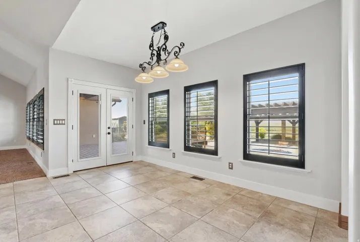 Spacious room featuring neutral-toned tile flooring, white walls, and a vaulted ceiling