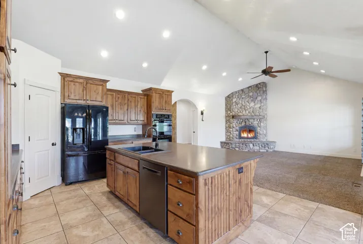Open-concept kitchen featuring wood cabinetry, a central island with integrated sink, tile flooring, and recessed lighting