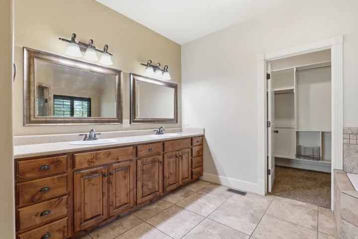 Bathroom featuring a double vanity with wood cabinetry and countertop, dual framed mirrors, and tile flooring