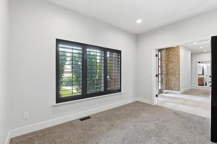Room featuring dark-framed windows with plantation shutters, recessed lighting, and light-colored carpeting