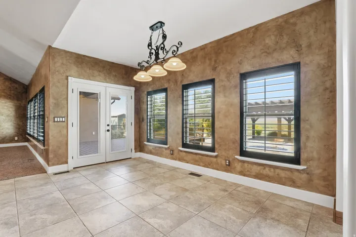 Textured walls with a decorative chandelier, tile flooring, and white baseboards