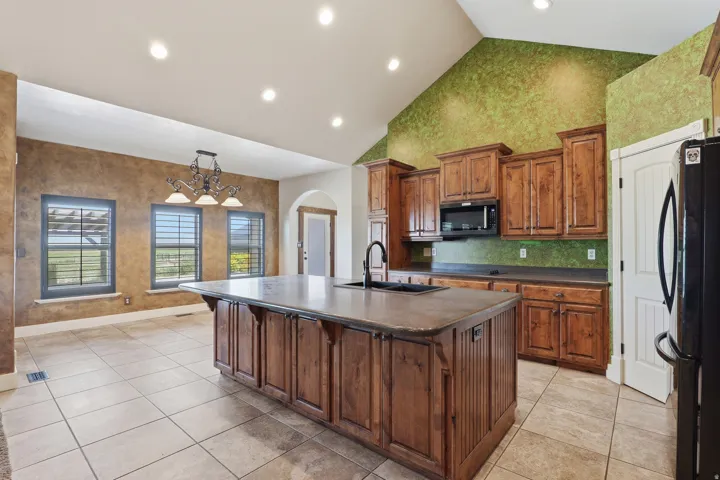 Kitchen featuring a large central island with integrated sink, wood cabinetry, and a black microwave