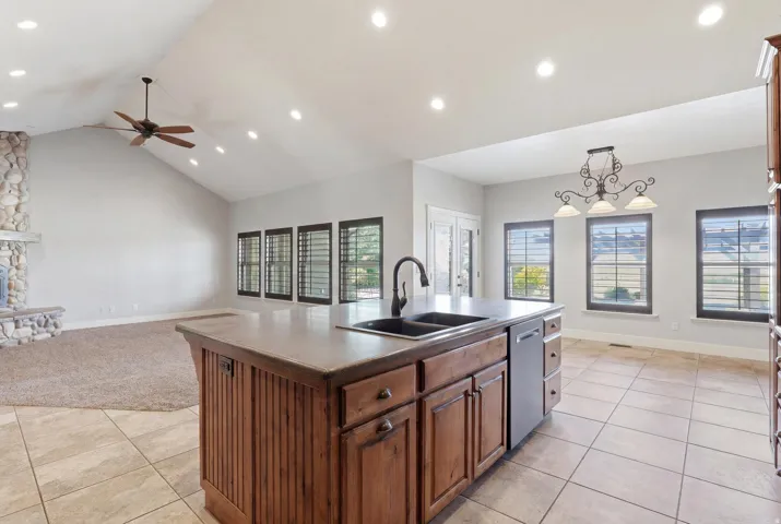 Kitchen island featuring a double basin sink, dishwasher, and wood-finish cabinetry