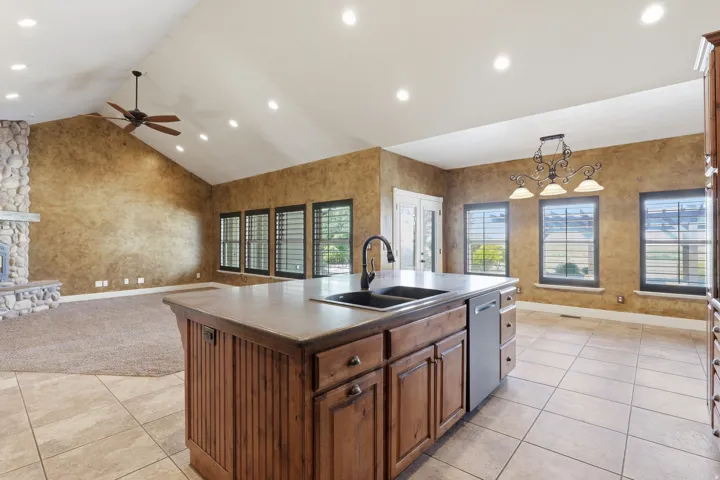 Spacious interior featuring a kitchen island with integrated sink, stainless steel dishwasher, and built-in cabinetry