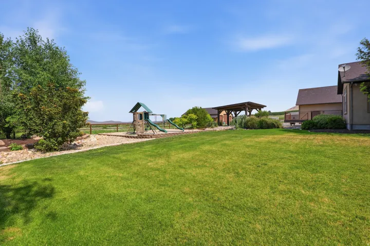 Expansive green lawn featuring a built-in play structure and a gravel border