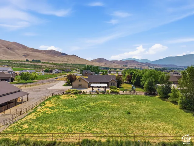 Expansive property featuring a large green space, a tan-sided residence with a covered patio, and a separate barn structure