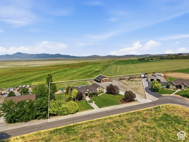 Expansive property featuring a prominent residence with attached garage, a separate barn structure, and substantial cleared land
