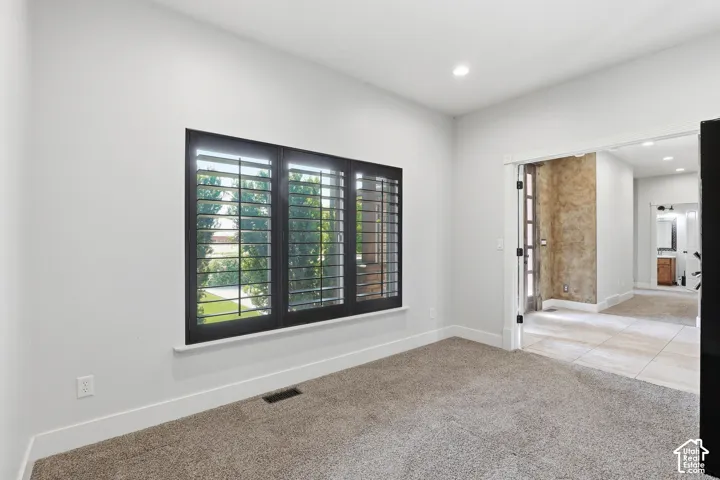Room featuring dark-framed windows with plantation shutters, recessed lighting, and light-colored carpeting
