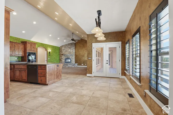 Expansive kitchen and dining area featuring ceramic tile flooring, a large island with wood cabinetry, and a black appliance package