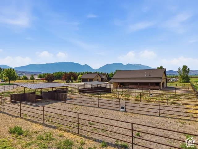 Expansive property featuring multiple fenced enclosures, a large barn structure, and a covered shelter with solar panels