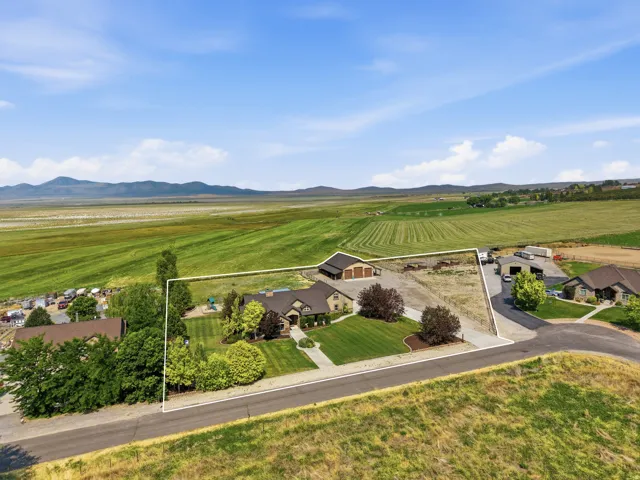 Expansive property featuring a prominent residence with attached garage, a separate barn structure, and substantial cleared land