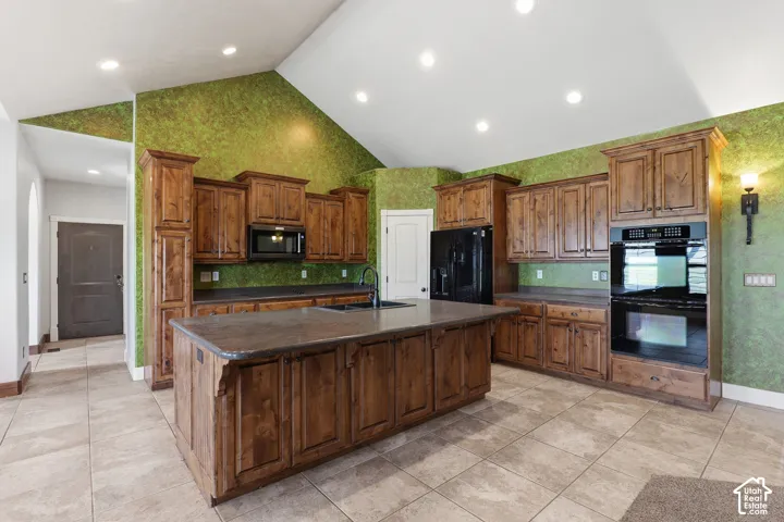 Kitchen featuring wood cabinetry, a central island with integrated sink, black appliances including a double oven and microwave, and recessed lighting