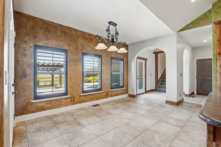 Spacious room featuring tile flooring, three windows with louvered blinds, and a decorative light fixture
