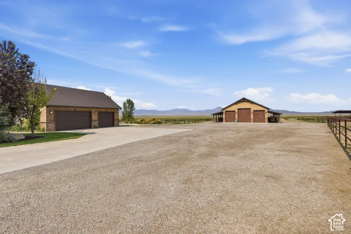 Expansive gravel grounds featuring a multi-bay barn structure, a separate two-car garage building, and perimeter fencing