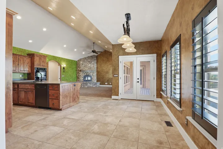 Expansive kitchen and dining area featuring ceramic tile flooring, a large island with wood cabinetry, and a black appliance package