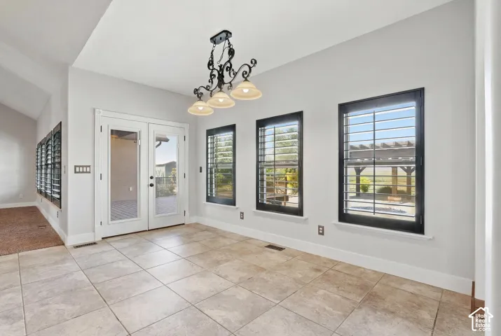 Spacious room featuring neutral-toned tile flooring, white walls, and a vaulted ceiling