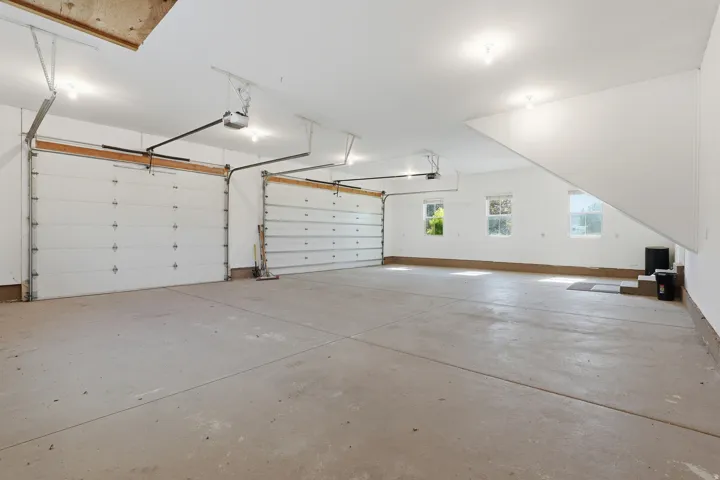 Spacious two-car garage with concrete flooring, multiple windows, and overhead lighting