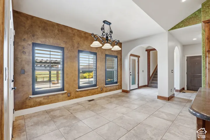 Spacious room featuring tile flooring, three windows with louvered blinds, and a decorative light fixture