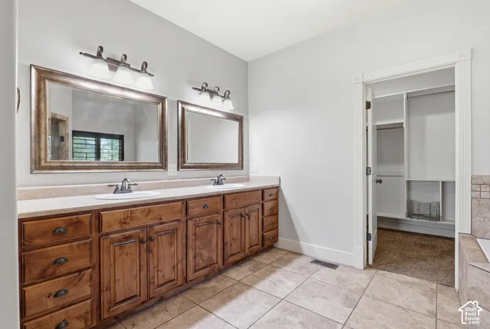 Double vanity featuring wood cabinetry, integrated sinks, and individual mirrors with overhead lighting