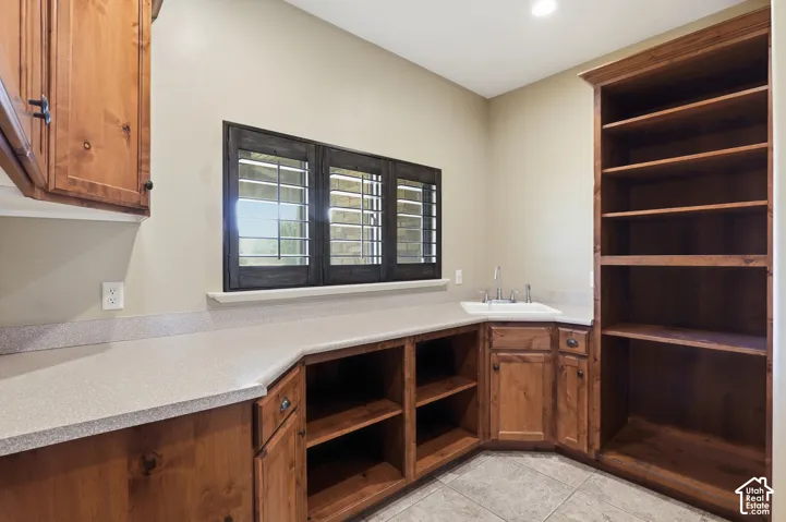 Functional utility space featuring extensive wood cabinetry, a recessed sink, and built-in shelving