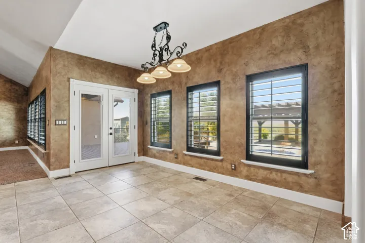 Textured walls with a decorative chandelier, tile flooring, and white baseboards