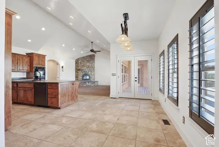 Spacious open-concept interior featuring light-colored tile flooring, a large kitchen island with wood cabinetry, and a stone fireplace