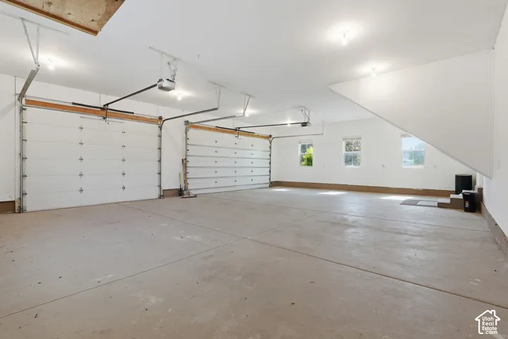 Spacious two-car garage with concrete flooring, multiple windows, and overhead lighting