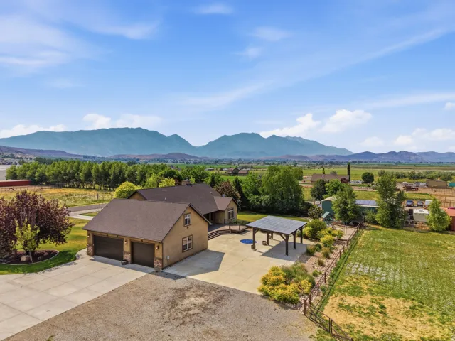 Expansive property featuring a detached garage with dual doors, a covered patio structure, and a large concrete driveway