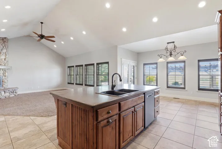 Kitchen island featuring a double basin sink, dishwasher, and wood-finish cabinetry