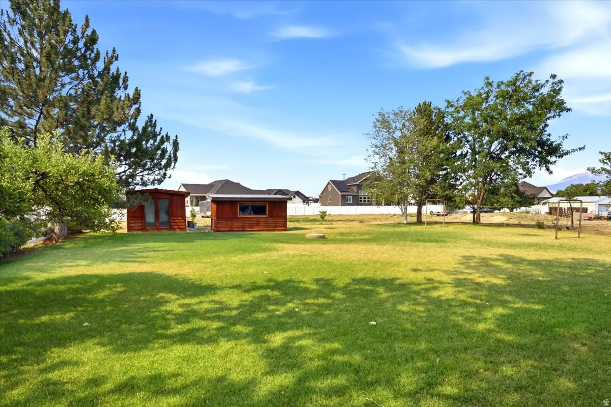 Expansive green lawn with two wood-clad outbuildings