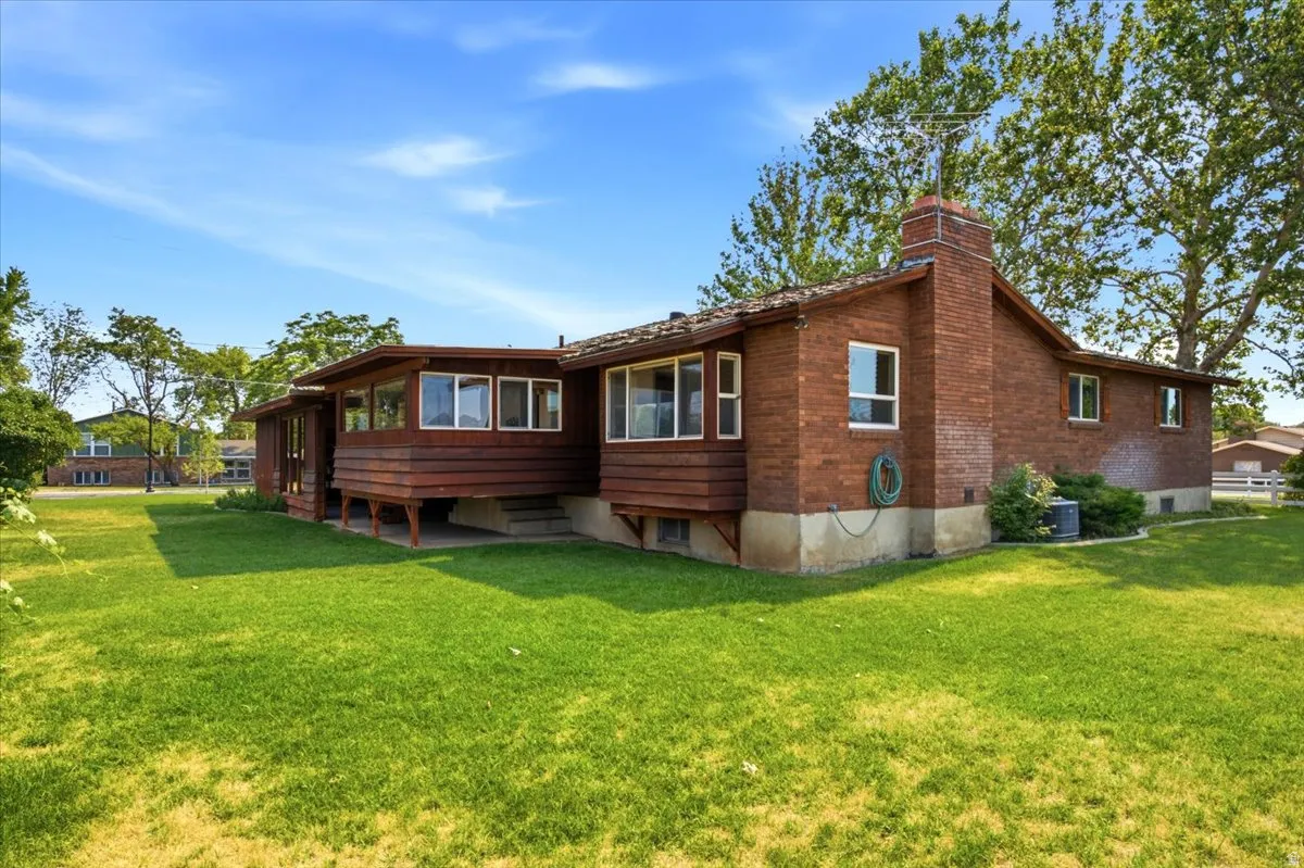 Brick exterior property featuring a sunroom with multiple windows and wood-clad lower panels