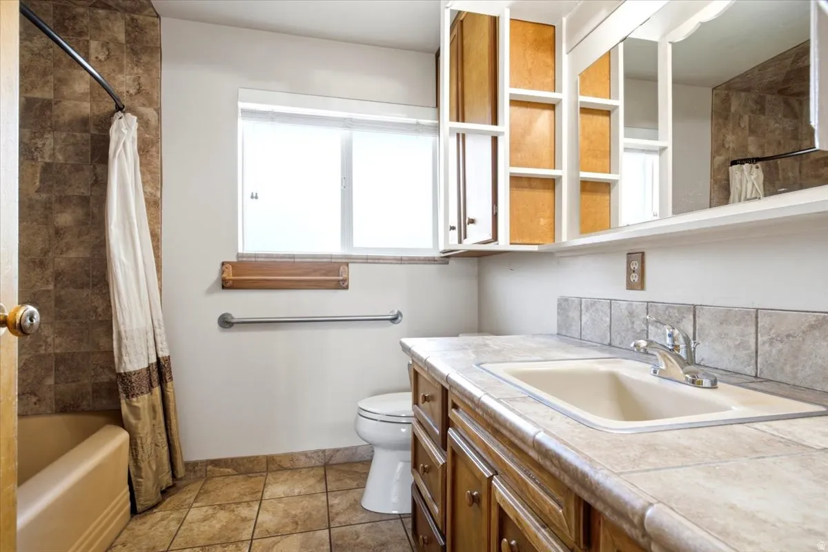 Full bathroom featuring a single vanity with an integrated sink, tile countertop, and a tile backsplash