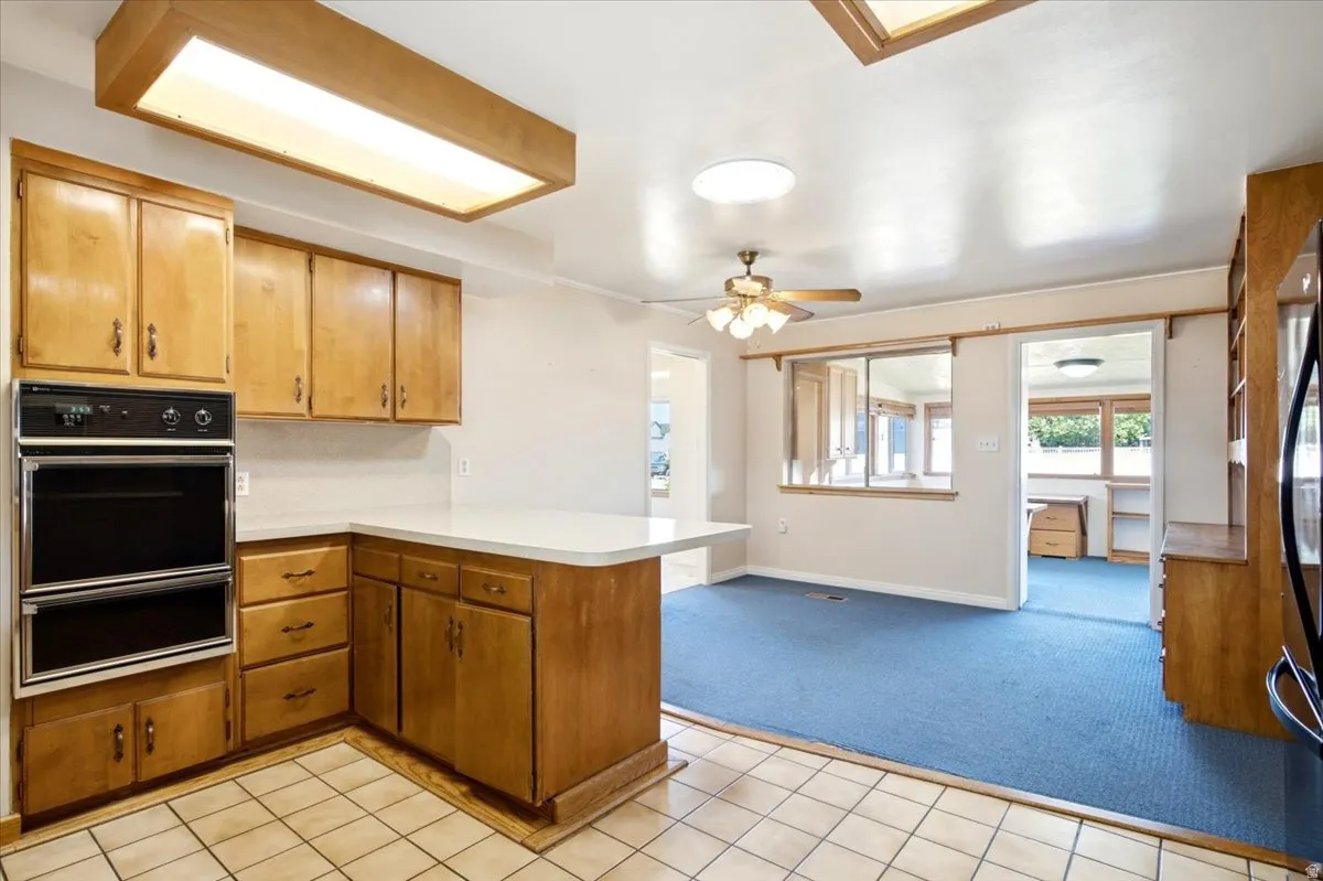 Kitchen with light wood cabinetry, white countertops, and a built-in double oven