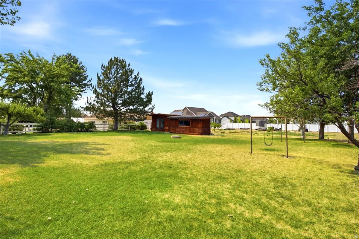 Expansive grassy yard featuring mature trees and a swing set