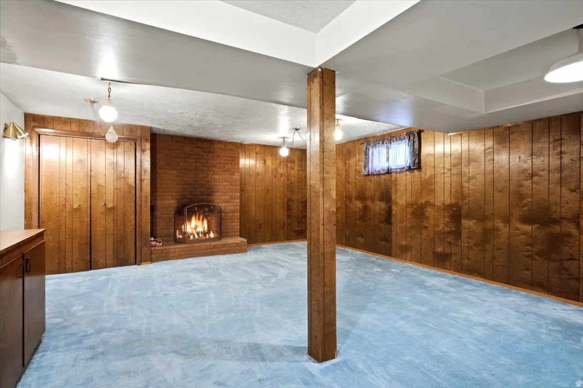 Spacious room featuring wood paneling, a brick fireplace, built-in cabinetry, and integrated lighting fixtures