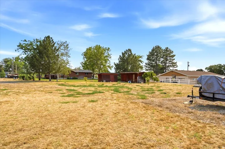 Expansive undeveloped land with mature trees and visible perimeter fencing