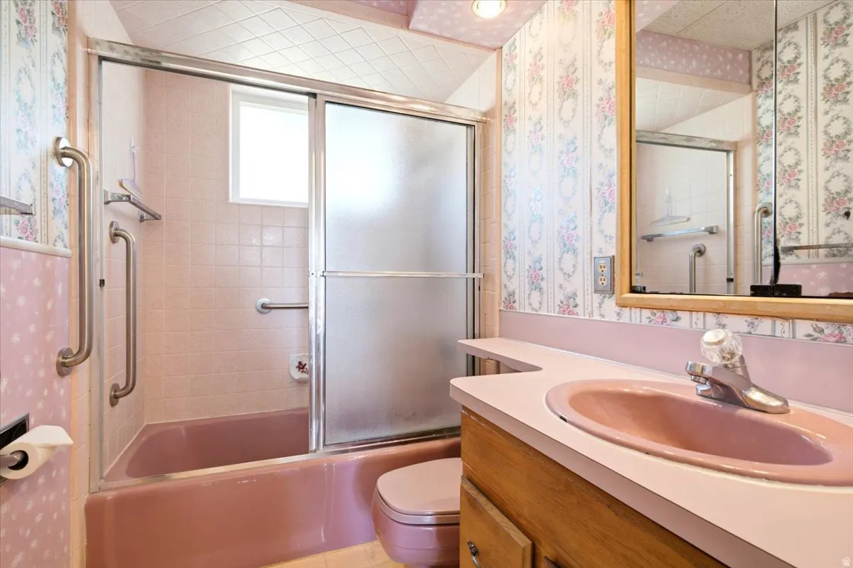 Bathroom featuring a pink tub and sink with the pink wallpaper! Cause .... it's a Grandma House, right?!?!