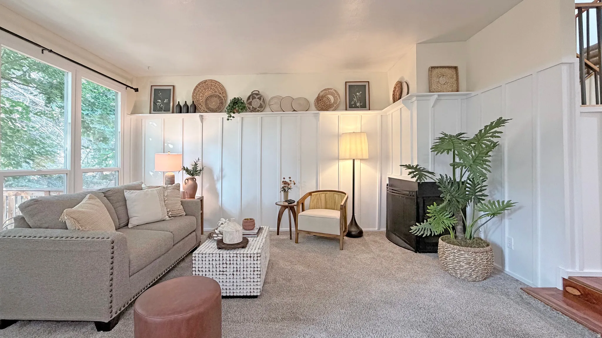 Living area featuring board and batten wall paneling, light-colored carpet, large windows, and a built-in shelf