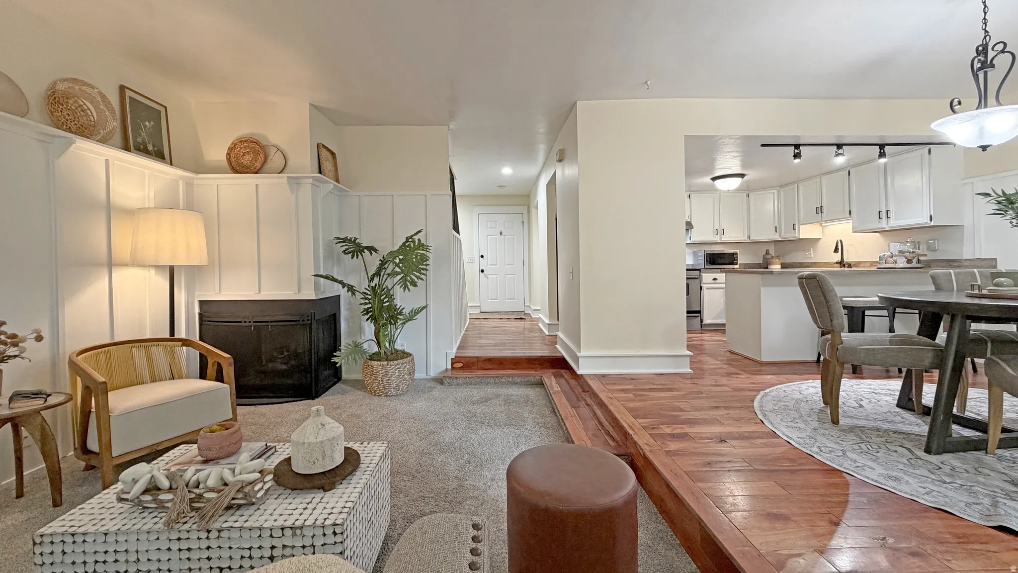 Living area featuring a fireplace with black screen, white wainscoting, and carpet flooring