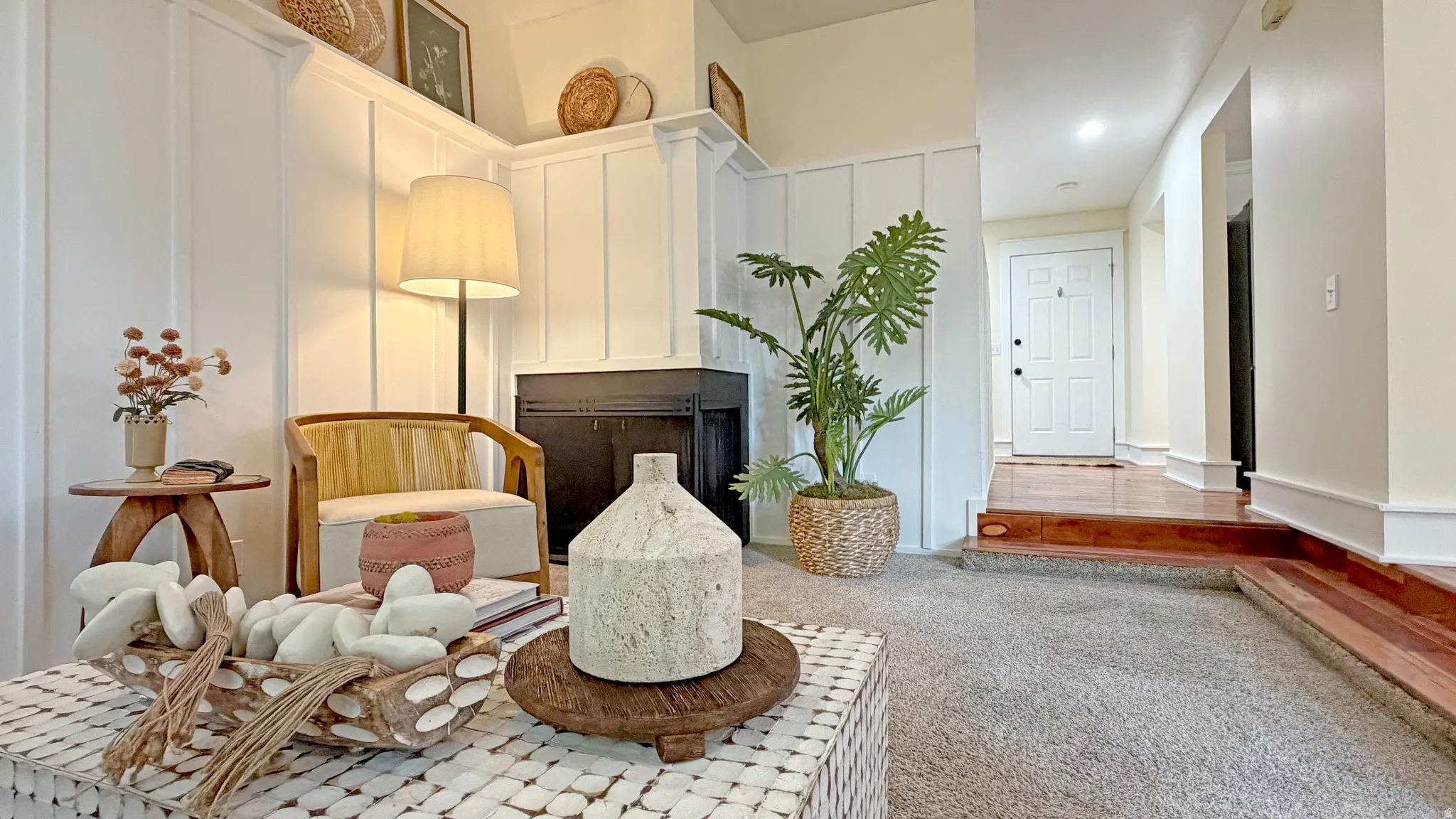 Living area featuring a fireplace with a black surround, white board and batten wall paneling, and a mantel