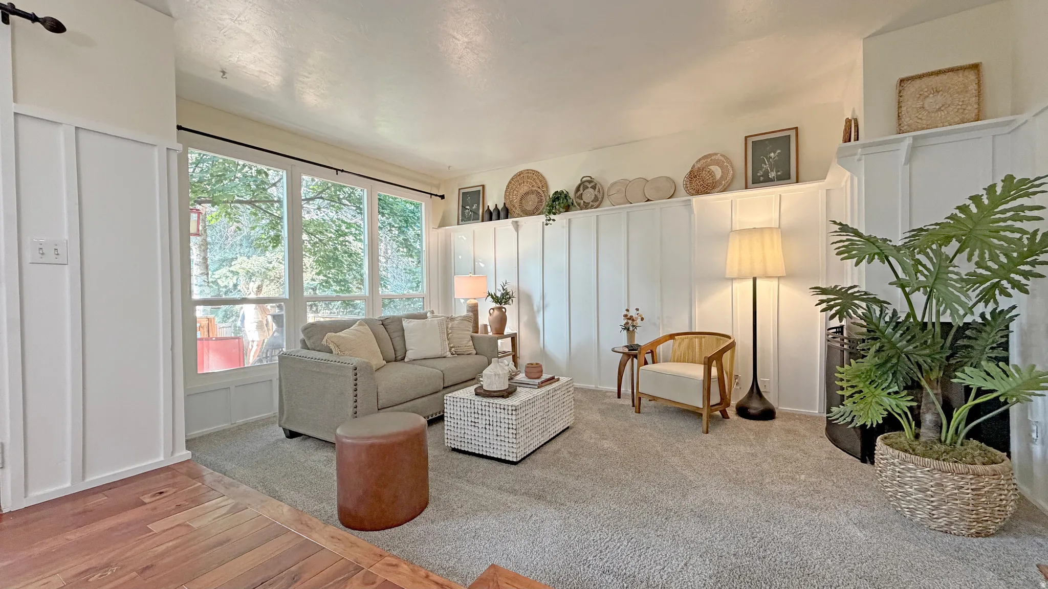 Living area featuring a floor-to-ceiling fireplace with a white mantel, white board and batten paneling, expansive windows, and light-colored carpeting