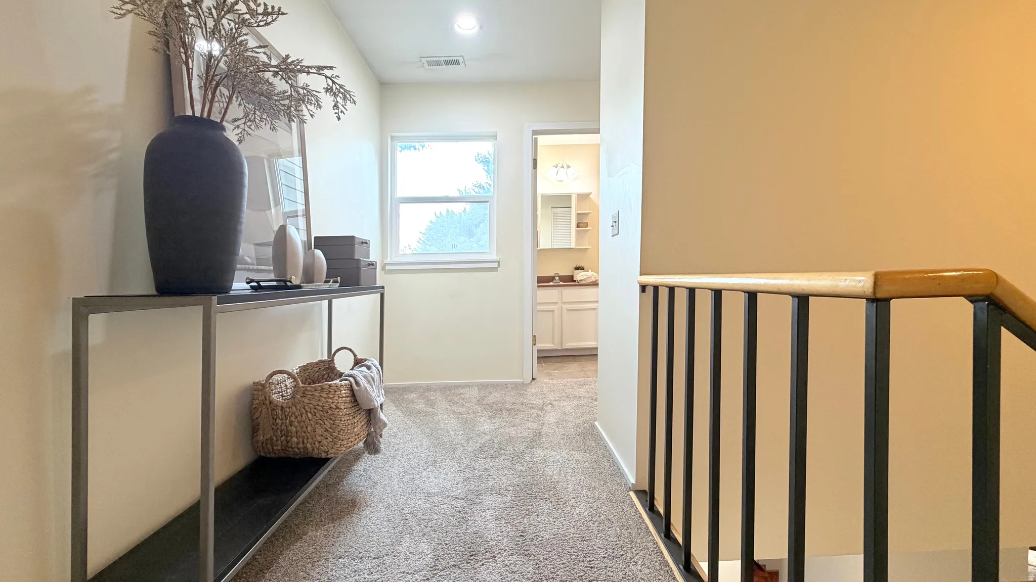 Carpeted hallway with a single window and neutral wall tones