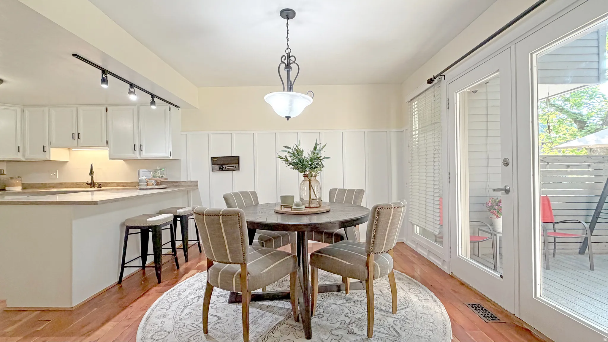 Dining area with hardwood flooring, board and batten wainscoting, and a decorative pendant light fixture